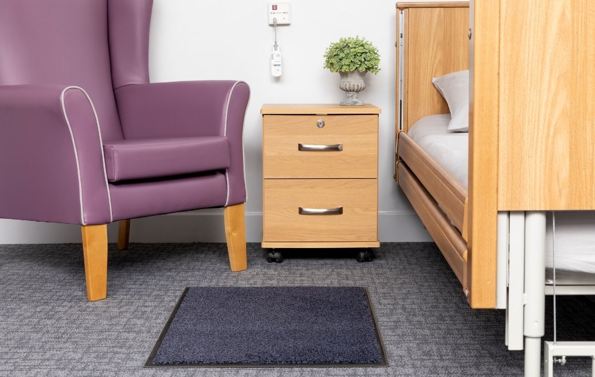 wireless blue alertamat on carpetted flooring next to bed