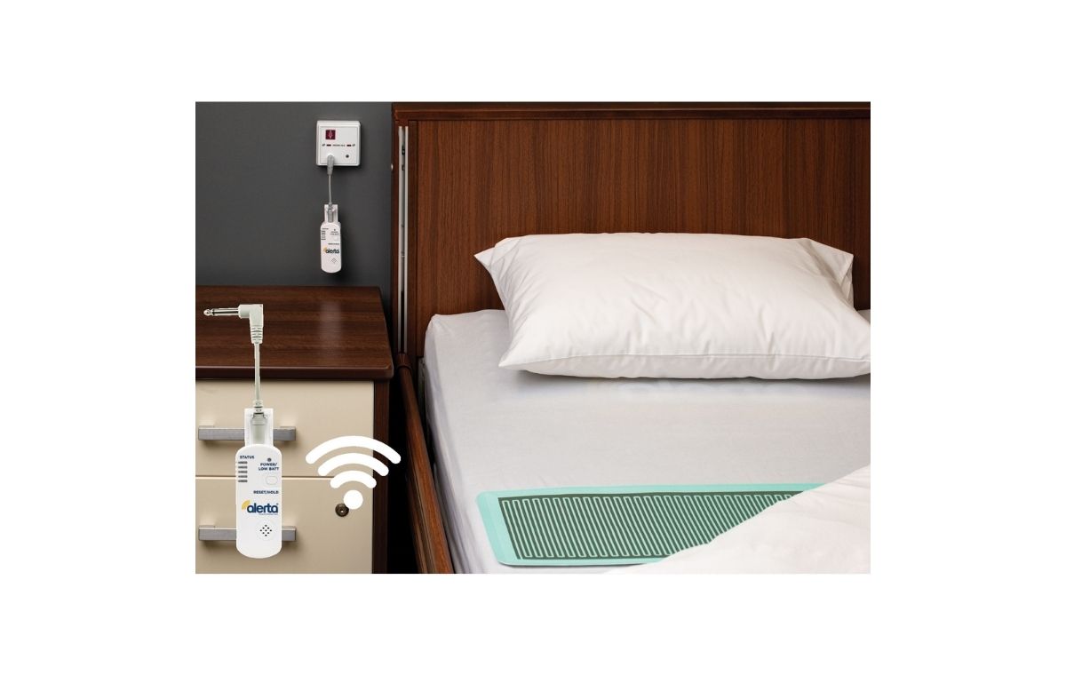 Wireless WetSense Bed Alertamat on top of fitted bed sheet next to bed side table with wall point reciever